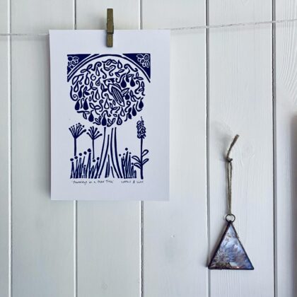 Partridge in a pear tree a5 blue linocut print hanging on display