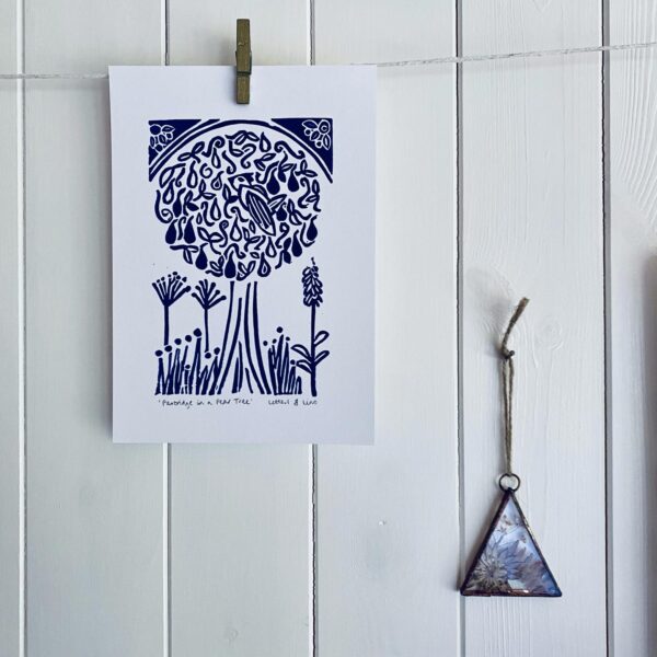 Partridge in a pear tree a5 blue linocut print hanging on display